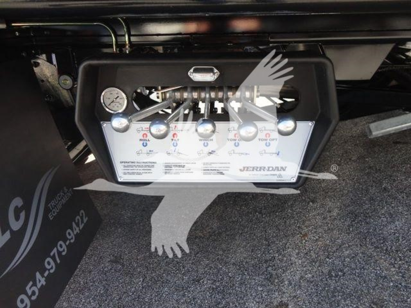 Panel with gauges and control valves labeled with GPM/PSI and letters; a hydraulic manifold with several levers and a small gauge, mounted under a truck, with a Jaz Jordan label.