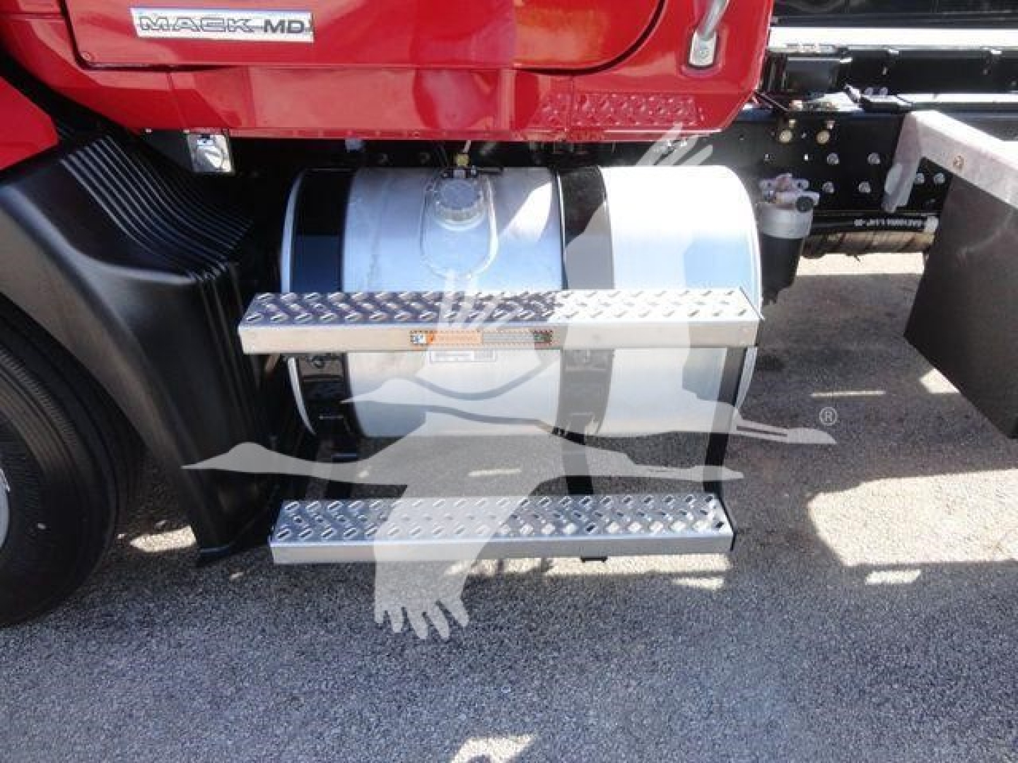 Mack MD6 truck side view showing chrome fuel tank, metallic diamond-plate steps, and side rail; badge reads 'MD6' on red cab.