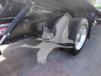 Truck chassis and dual rear axle with large tire profile, side view showing frame rails and suspension components under a 2027 Mack MD6 rollback truck.