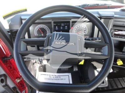 Mack MD6 truck cockpit showing steering wheel and dashboard gauges, central display, and control stalks.