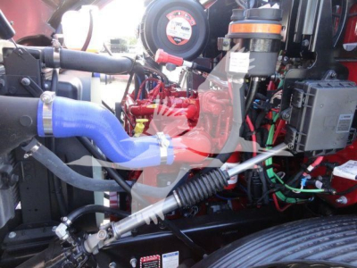 Mack MD6 engine bay showing blue intercooler hose, red engine block, wiring harness, and various components in a rollback truck.