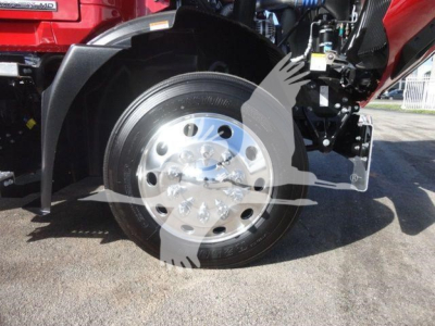 Mack MD6 truck front wheel and fender area showing polished aluminum wheel and tire with red cab in background.