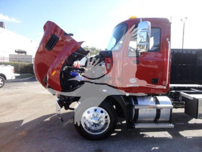 Truck cab with hood open showing engine bay and chrome fuel tank under a red Mack MD6 semi-tractor