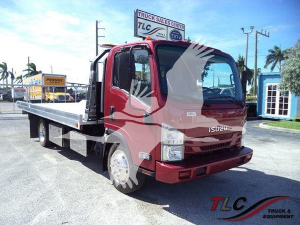 Isuzu NPR XD tow truck in red with flatbed, front view showing cab and extended flatbed at a dealership lot.