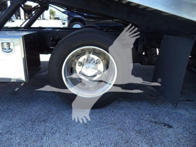 Isuzu NPR XD rollback truck rear wheel and suspension with chrome hubcap and black mudguard.