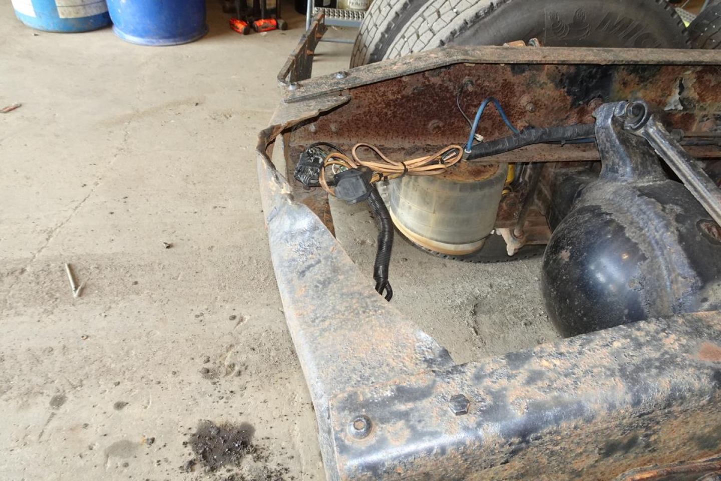 Freightliner M2 112 chassis showing exposed cab mount area with rust, electrical wires, and a translucent reservoir.