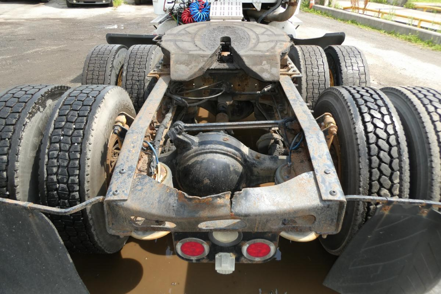 Freightliner M2 112 chassis rear view showing dual rear axles and fifth wheel area with rusted metal frame and tires.