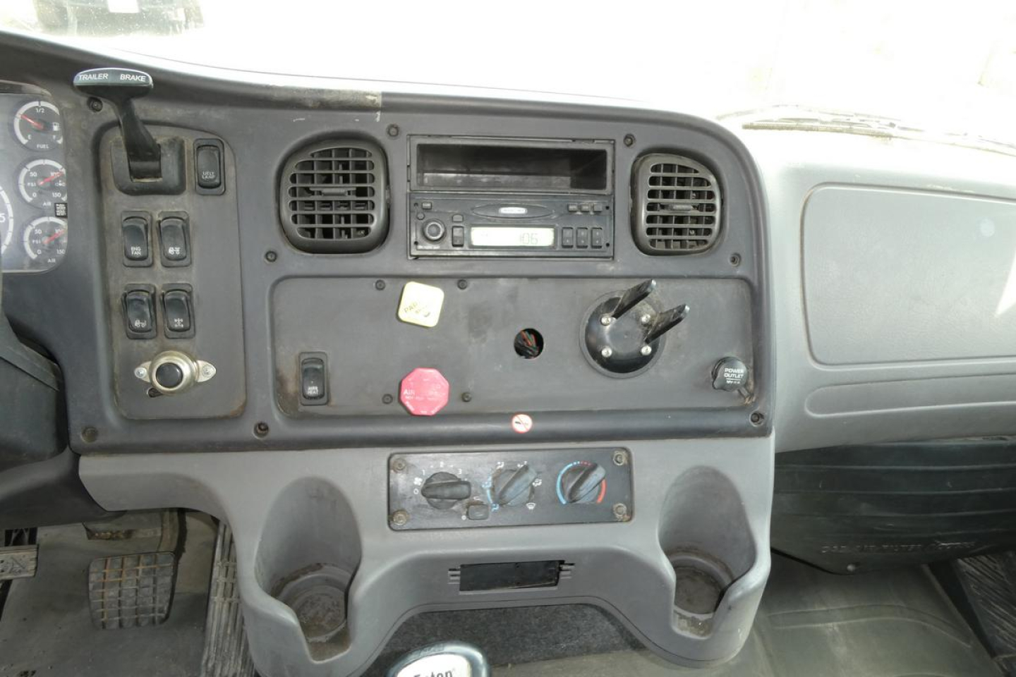 Dashboard panel of a Freightliner M2 112 daycab showing radio, vents, knobs, and switch cluster.