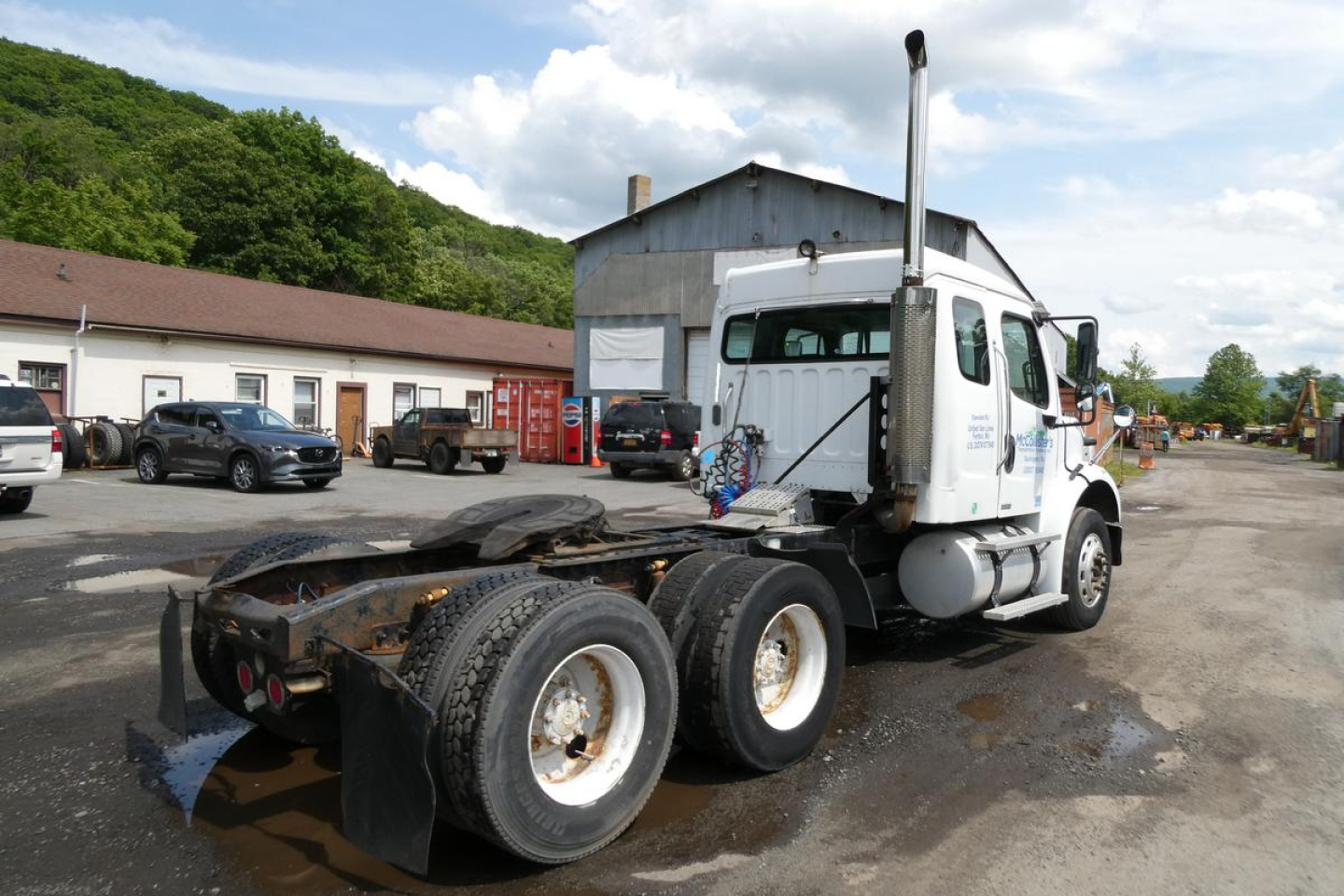 Freightliner M2 112 truck axle rear view showing five wheels and chassis with mud tires.