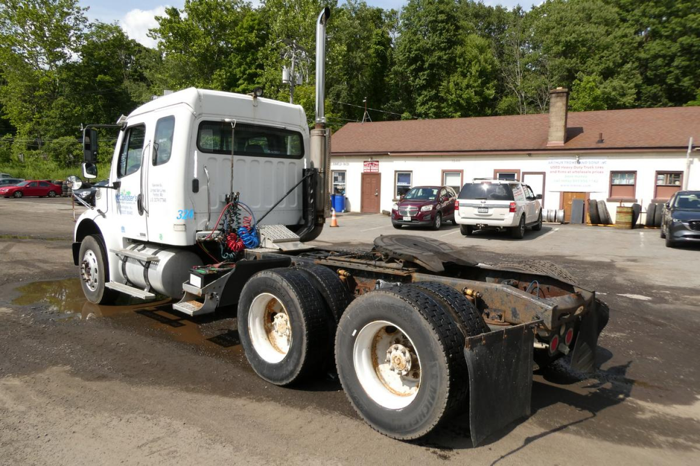 Truck chassis showing Freightliner M2 112 cab with chassis and dual rear axles, side view.
