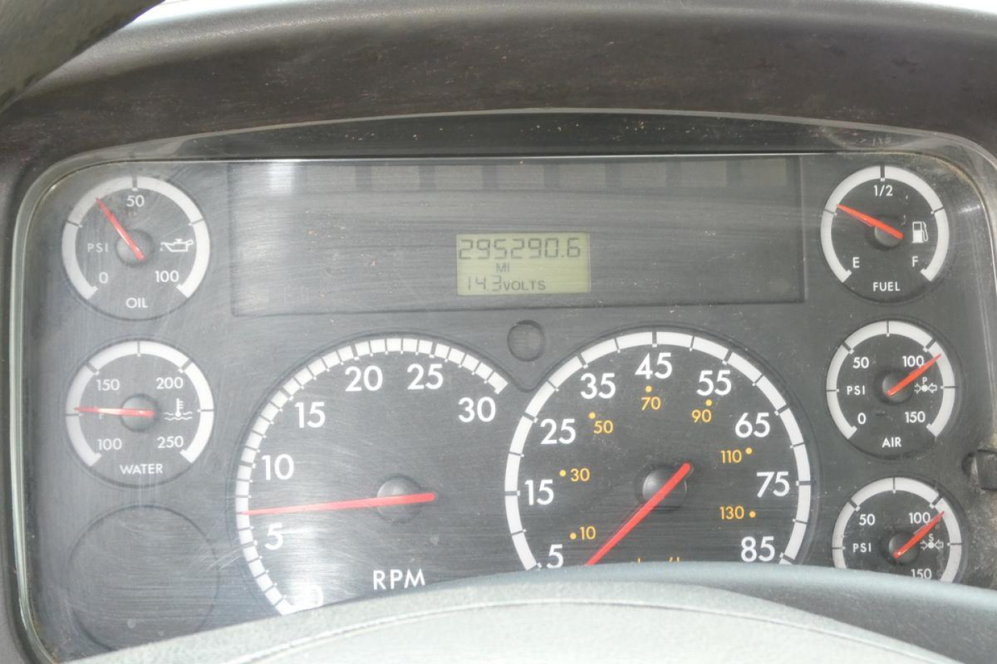Dashboard of Freightliner truck showing analog gauges including RPM and speedometer, with digital odometer reading 295,380.6 and various scales for oil, water, fuel, PSI, and temperature.