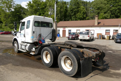 Truck chassis showing Freightliner M2 112 cab with chassis and dual rear axles, side view.