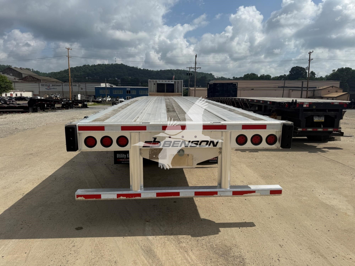 Flatbed trailer back view showing Benson logo and rear lights in an outdoor lot.