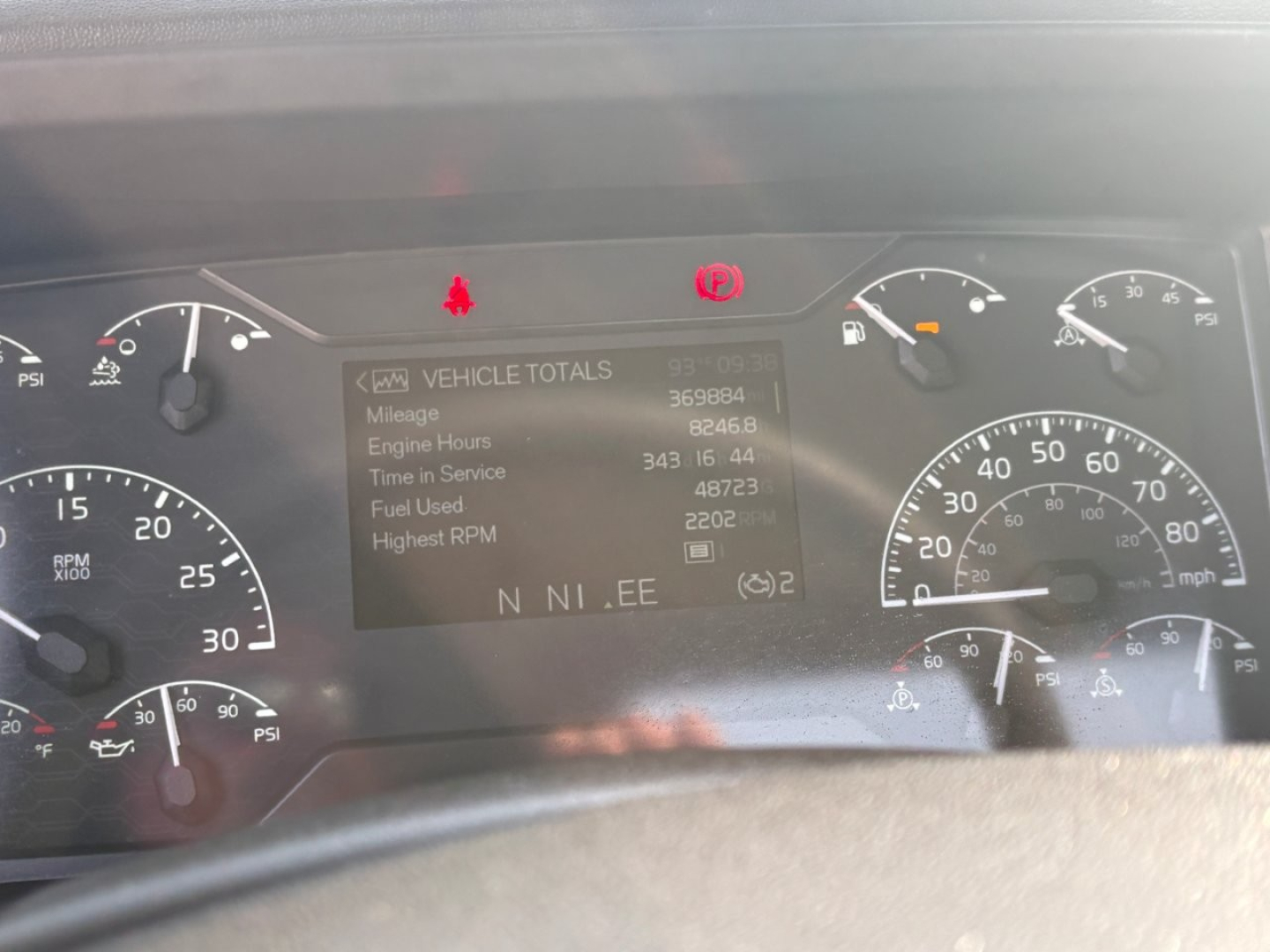Instrument cluster of a Volvo VNR truck showing dashboard display with Vehicle Totals data and gauges around.