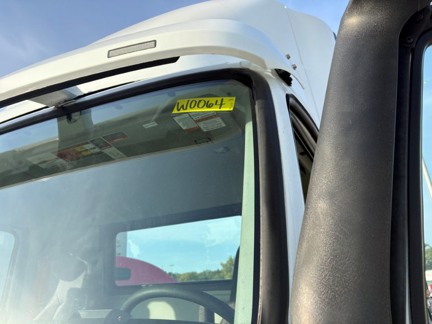 Volvo VNR64T300 cab interior and windshield area with yellow stock sticker  A006047 visible on the upper windshield