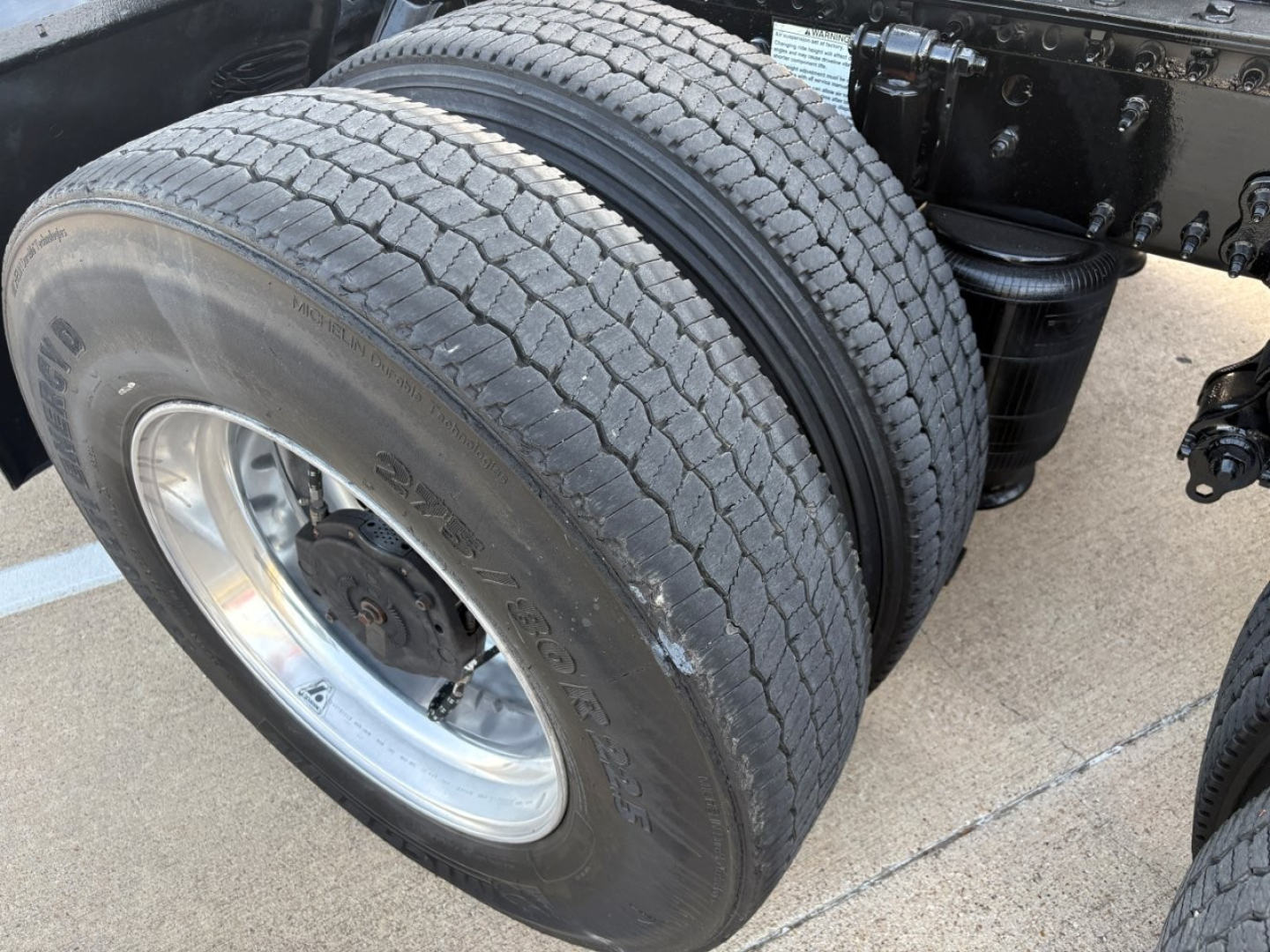 Volvo VNR64T300 truck wheel/tire assembly showing dual rear axle with large tread and rim, chassis components visible.