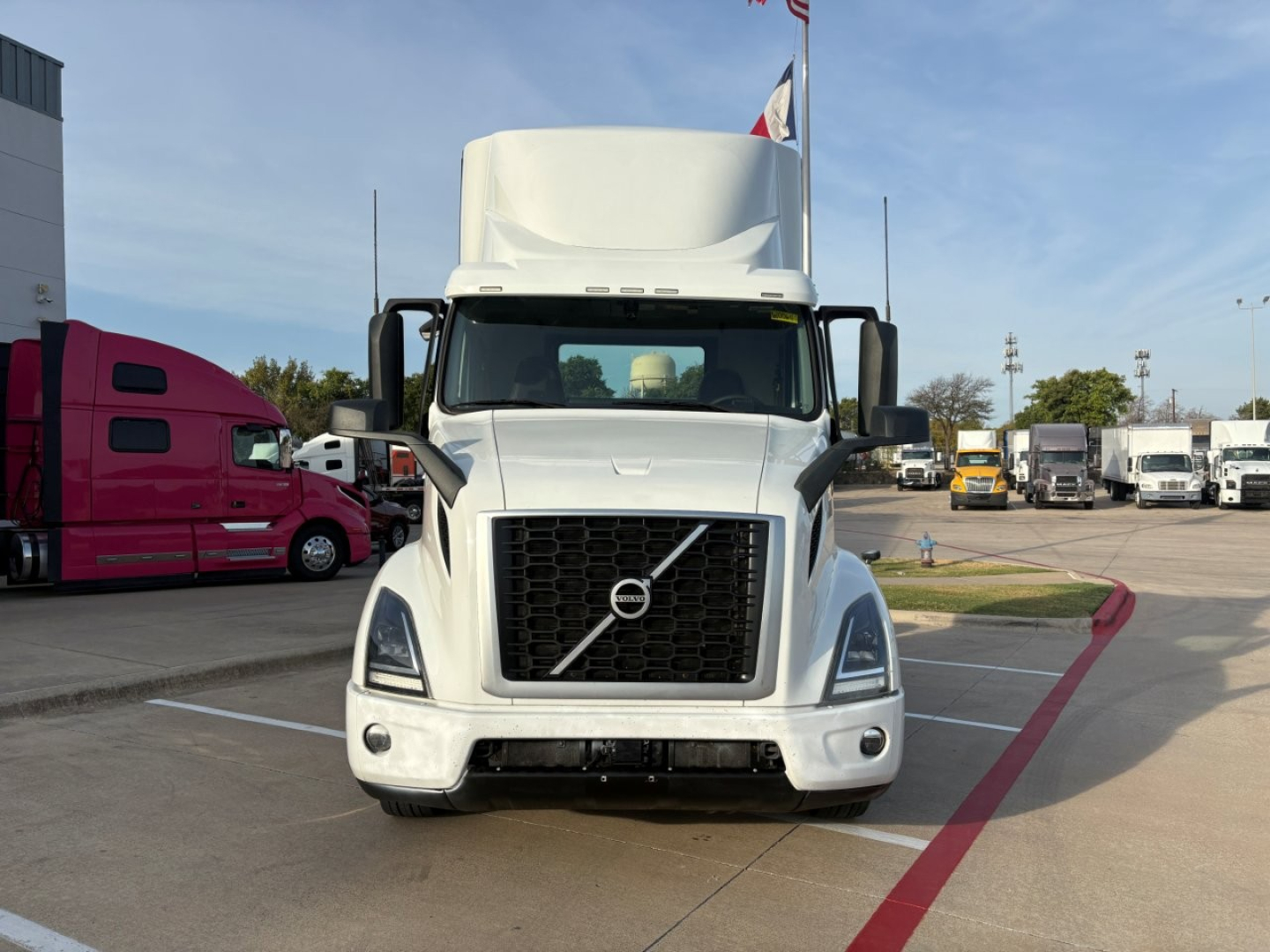 Front view of a white 2022 Volvo VNR64T300 semi-truck in a dealership lot, with large grille, Volvo emblem, and sleeper cab overhang visible.