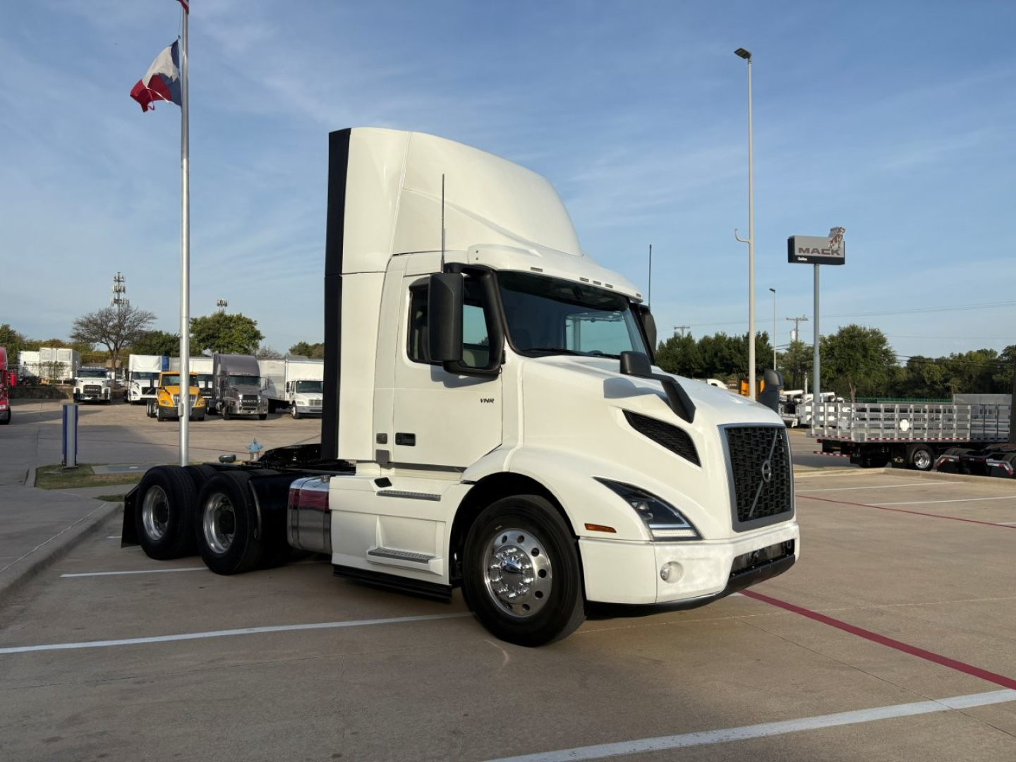 Volvo VNR64T300 tractor unit side view showing cab and front grille with large mirrors in a dealership lot.