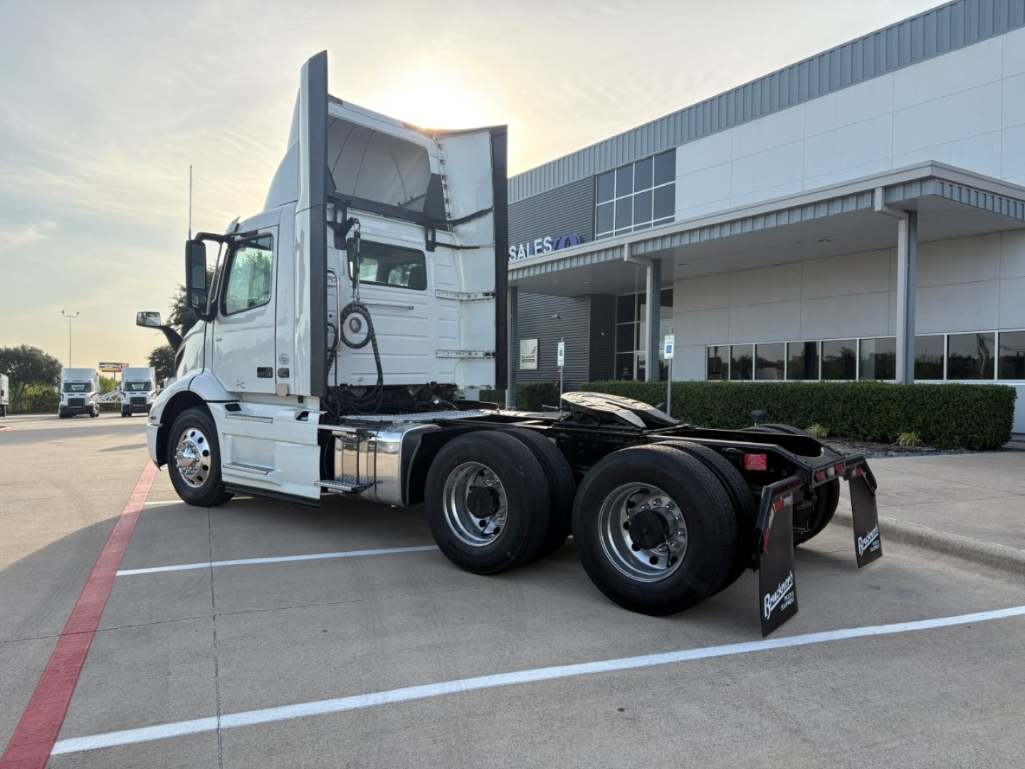Volvo VNR64T300 truck chassis and cab in a dealership lot showing rear wheels and sleeper area.