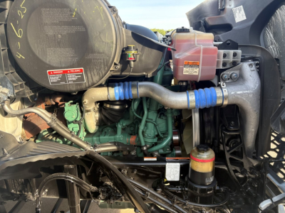 Volvo VNR engine bay showing coolant reservoir, engine block, hoses, and fluid reservoirs.