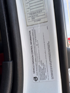 Vehicle emission control information label on a Volvo truck door jamb with VIN and engine info visible.