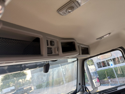 Cab interior overhead console with storage compartments and switches inside a 2022 Volvo VNR64T300 daytime cab