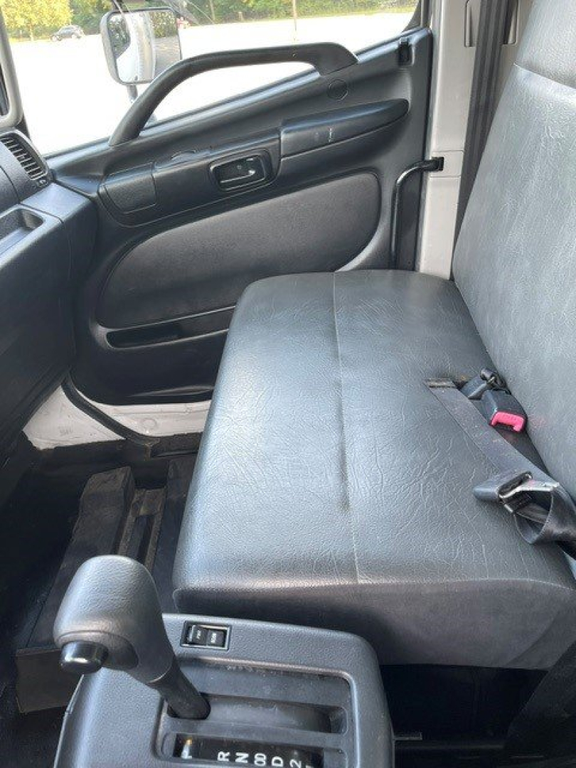 Seat belt and front passenger seat in a 2017 Hino 268 cab interior with black vinyl bench seat, door panel, and gear shifter visible.