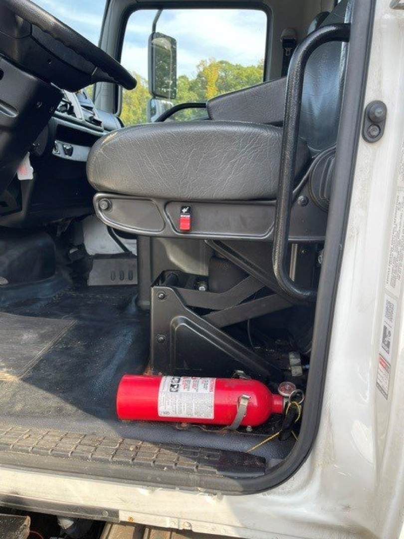 Cab interior of a 2017 Hino 268 truck showing driver seat, steering wheel, and a red fire extinguisher mounted near the door sill.