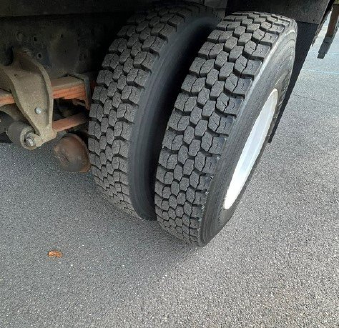 Dual rear tires on a Hino 268 truck showing tread detail and wheel. Part of rear axle and suspension visible.