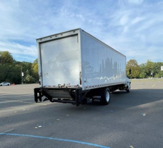 Box truck rear-view showing cargo trailer with closed roll-up door, Hino 2017 box truck with empty bed and rear underride guard.