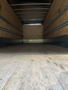 Truck cargo area showing interior of an empty box truck with wooden walls and metal rails, 2017 Hino 268 listing.