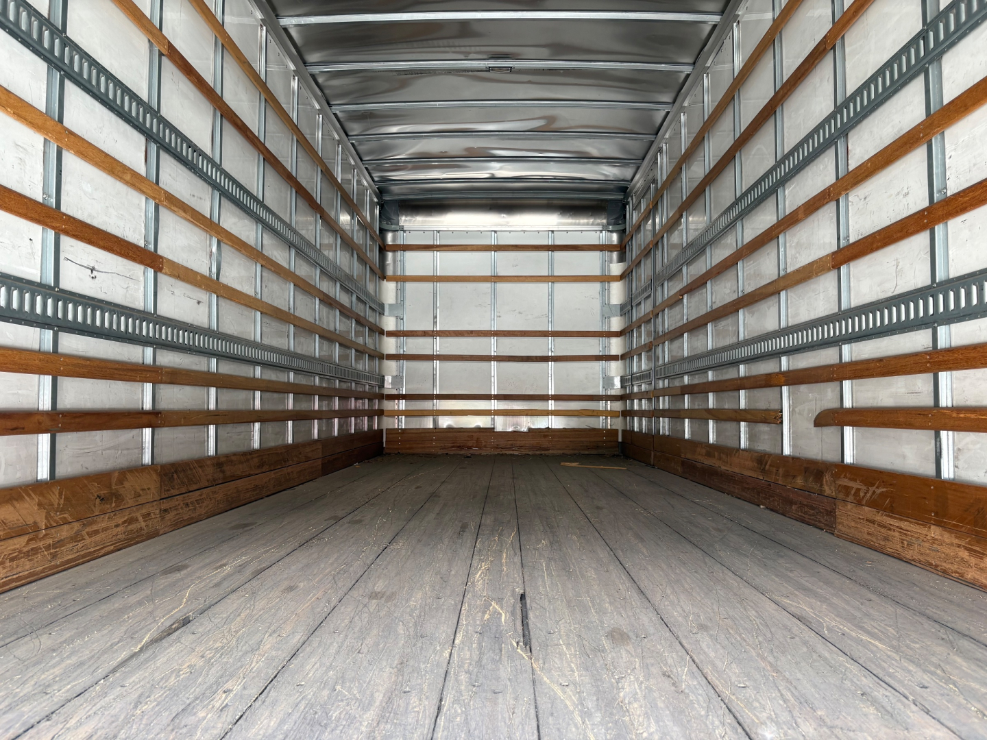Truck box interior showing empty cargo space with wooden floor and metal side rails.