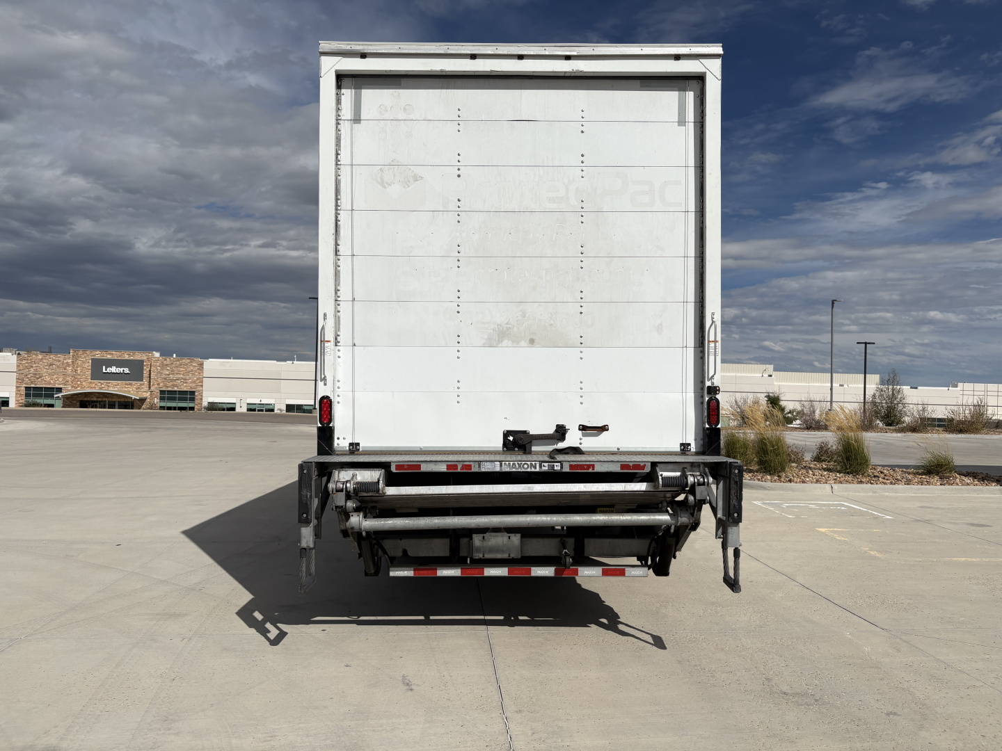 Freightliner M2-106 box truck rear view showing cargo area door with rear underride guard and bumper hardware.