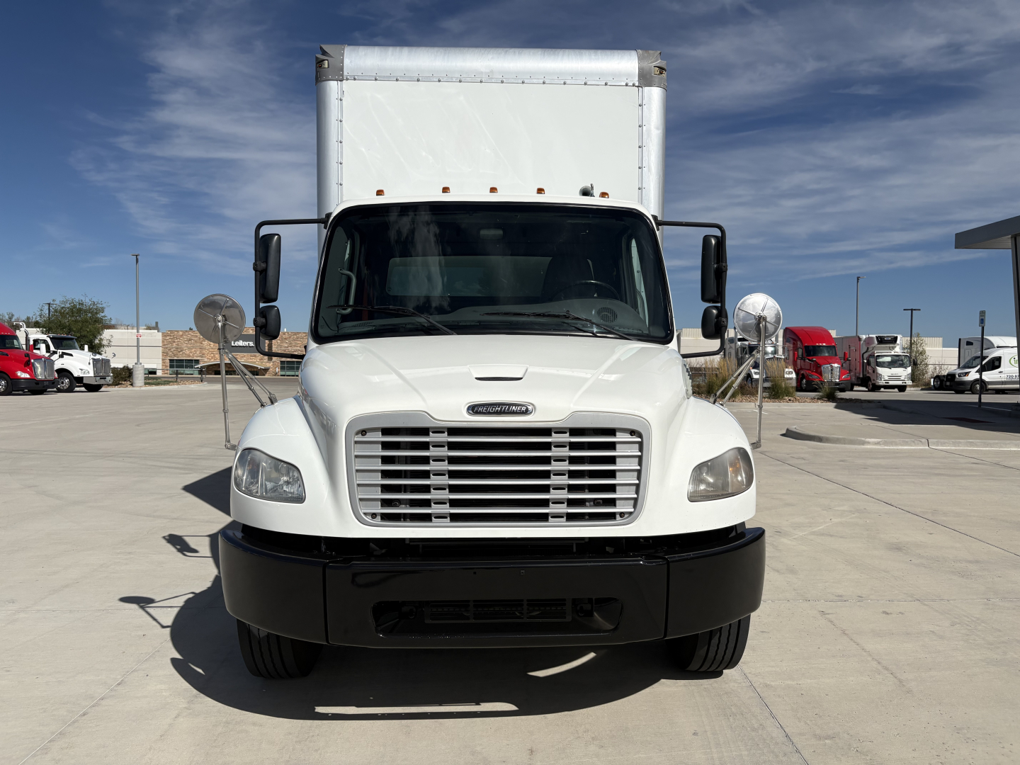 Front view of a white Freightliner M2-106 box truck showing grille, headlights, and large cargo box.