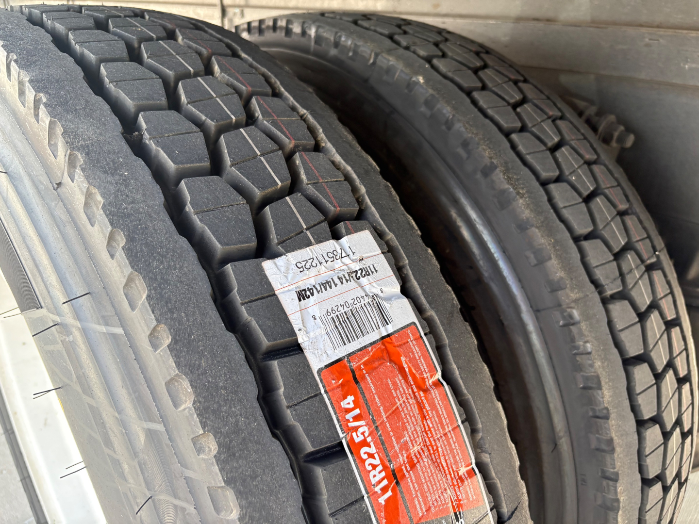 Two heavy-duty truck tires close-up with tread patterns visible and labels on the sidewall.