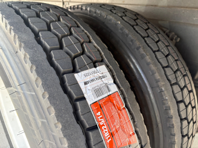 Two heavy-duty truck tires close-up with tread patterns visible and labels on the sidewall.