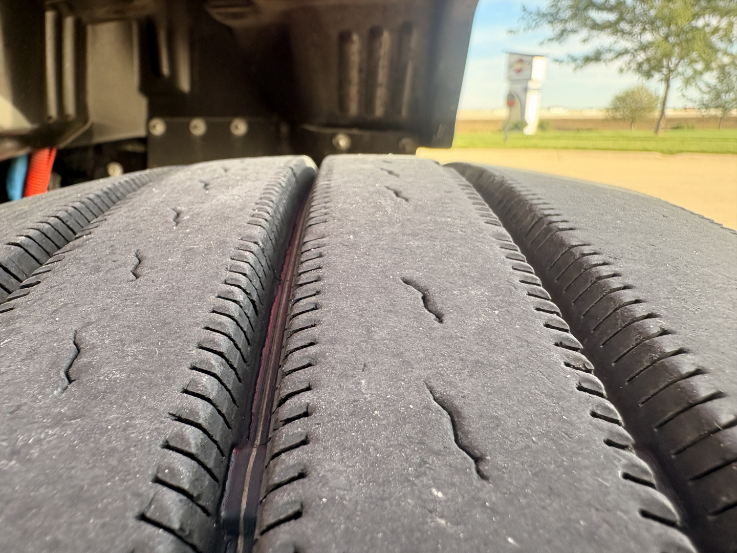 Kenworth T680 truck with close-up of dual rear tires and undercarriage components visible.