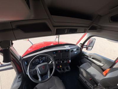 Cab interior of a Kenworth T680 2023 showing steering wheel, dashboard, and driver's seat from front passenger side.