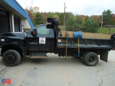 Truck side view showing a 2022 Chevrolet Silverado 6500HD dump truck with a V-plow, black exterior, dump bed, and tires; VIN label and equipment visible.