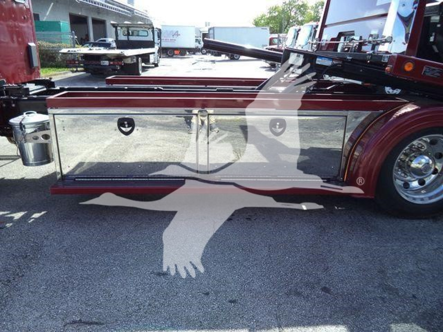 Rolback truck side storage box area showing chrome tool/storage compartments and maroon body with polished wheel.