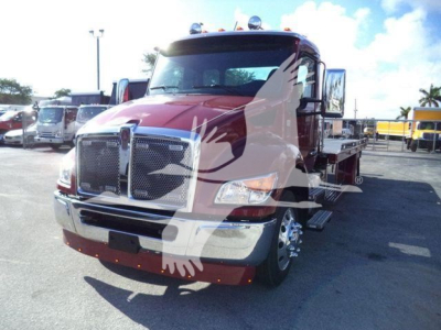 Kenworth T280 rollback truck with red cab and chrome grille, front view, on a dealership lot.