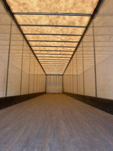 Trailer interior showing empty cargo van with wooden floor, side walls, and roof ribs; no visible text or labels inside.