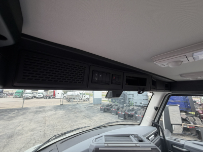 Inside cab of a 2027 Mack AN64T showing overhead instrument panel and storage area with vents and controls.