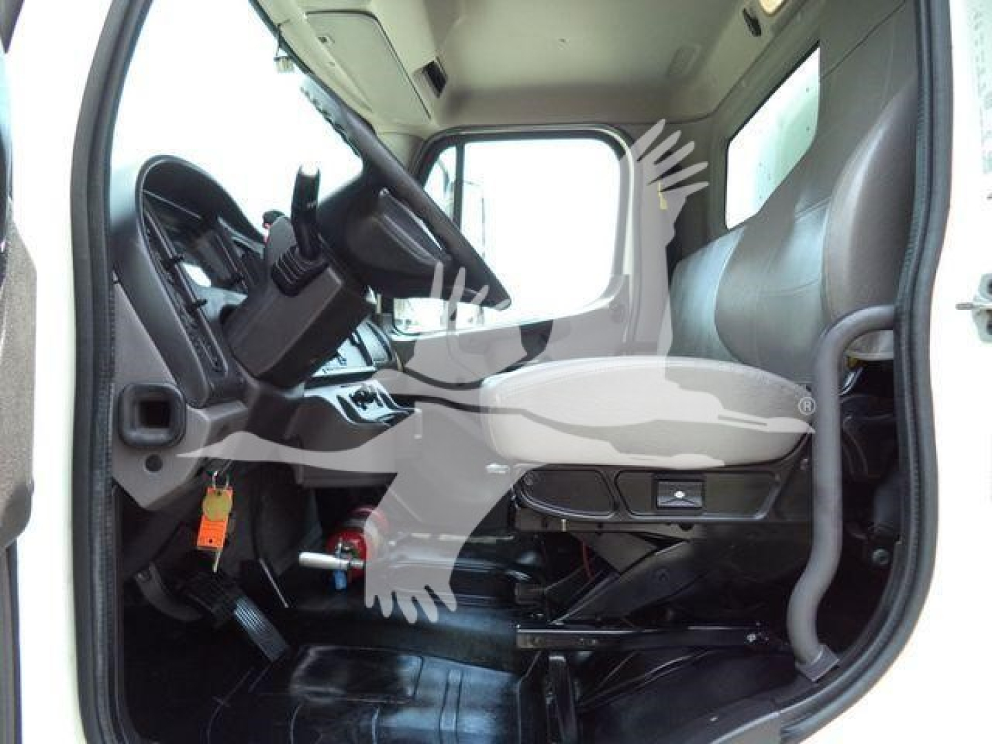 Freightliner M2 106 cab interior showing driver seat and dashboard with steering wheel and controls.
