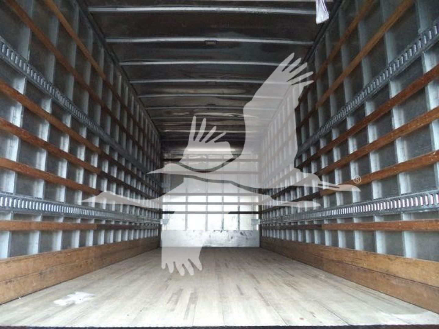 Interior empty box truck cargo area with wooden floor and metal side walls showing linear ribs.