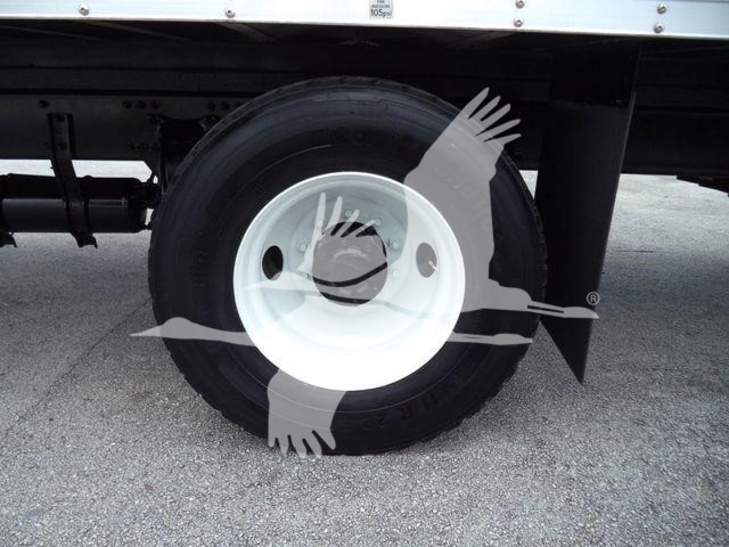 Freightliner M2 106 wheel and tire visible under side of box truck, white steel wheel with black tire.