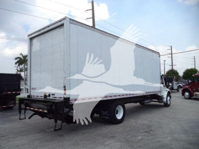 Box truck rear and side view showing Freightliner M2 106 cargo box with white exterior, dual rear wheels, and rear ramp/doors.