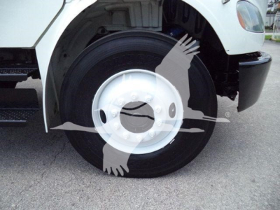 Truck front wheel and fender showing large white Freightliner M2 106 wheel with hub and black tire; partial bumper and step visible.