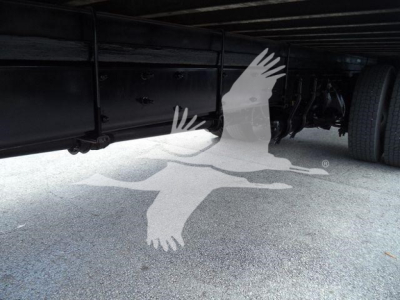 Underbody of a Freightliner M2 106 truck showing frame rail and wheel with a watermark overlay of birds
