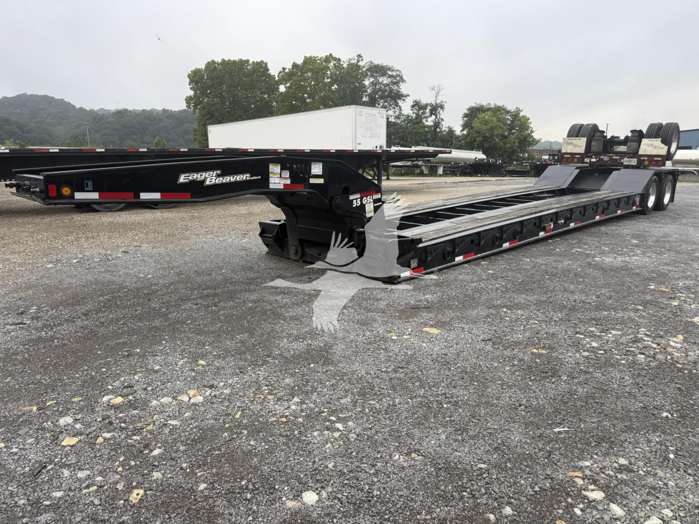 Trailer showing a lowboy form factor with a long black flatbed, dual rear axles, and ramp sections; visible labels include 'Eager Beaver' on the side.